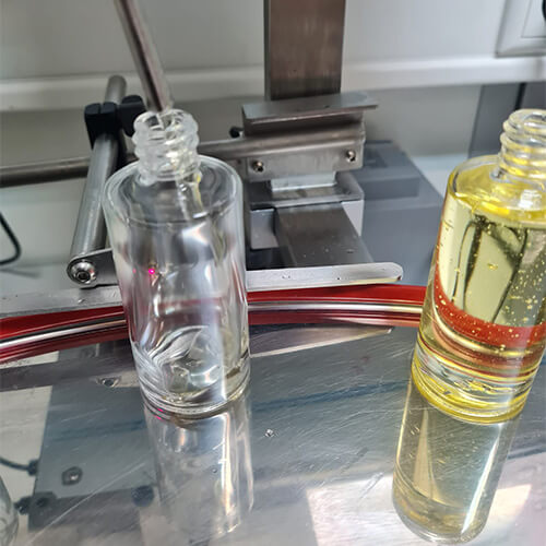 KENA Bio Mongongo-Öl Abfüllung im Labor in Deutschland in Glasflaschen. Eine Flasche wurde bereit abgefüllt, die andere wird gerade abgefüllt.