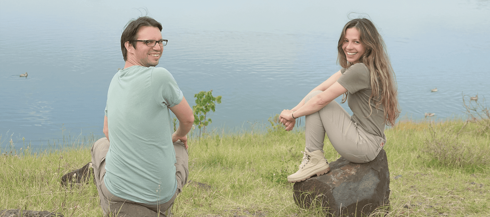 Die Menschen hinter KENA sitzen auf Steinen vor einem See in Afrika